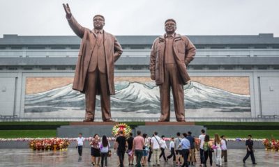Locals and tourist in front of the Northern Korea leader statue in a cloudy day | Defector Says Woke US Schools Nuttier Than North Korea | featured