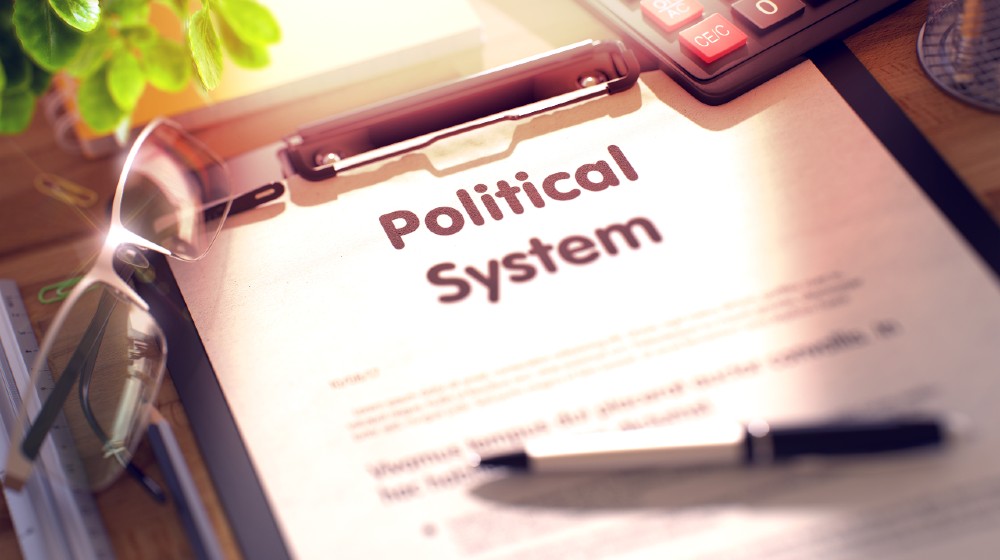 Political System on Clipboard. Office Desk with a Lot of Office Supplies | 5 Reasons Many Feel The American Political System Is Failing | featured