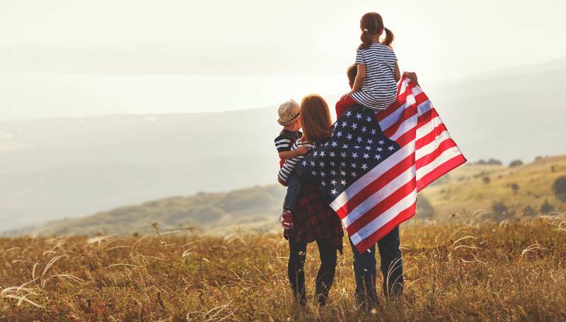 happy family with the flag of america USA at sunset outdoors | 5 Priorities For America To Address Now!