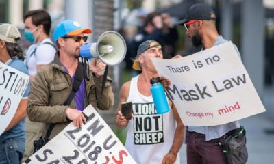 Anti-mask protesters holding signs related to COVID-19 | Former Surgeon General Says Updated CDC Mask Rules Are Wrong | featured