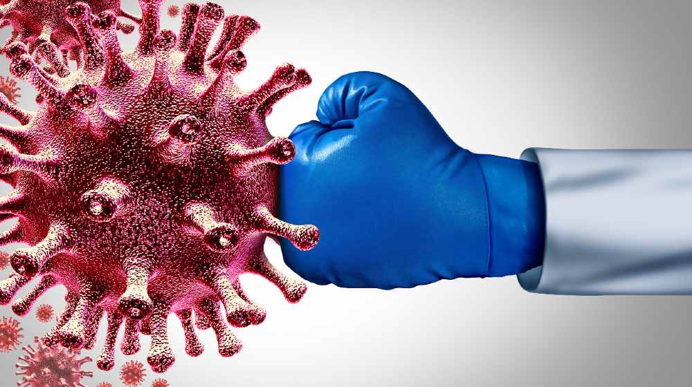 Virus vaccine and flu or coronavirus medical fight disease control as a doctor fighting a group of contagious pathogen cells | Politicising Covid-19 fight is perilous | featured