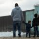 A family stands in front of the USA Mexico border wall | SC Orders Biden to Follow Trump’s ‘Remain in Mexico’ Policy | featured