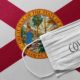 An individual face medical surgical mask on Florida State Flag Background | Florida Posts Record 21,683 COVID Daily Cases | featured