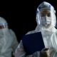 Doctor wearing PPE and face shield holding coronacovid-19 virus laboratory report in hands | NIH Director Warns US Can Reach 200k COVID-19 Cases Daily | featured