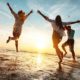 Four happy friends at sunset beach party runs to water | Are These The Keys To A Happier Life | featured