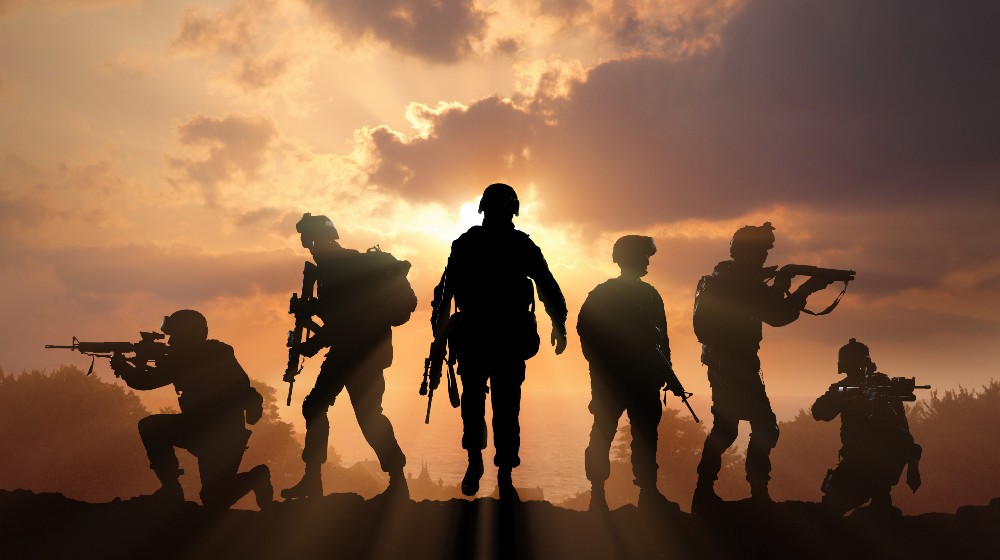 Six military silhouettes on sunset sky background | Biden Vows US Retaliation For Kabul Terrorist Attack | featured