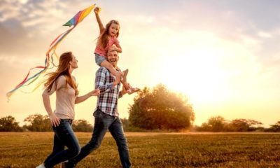 family running through field letting kite fly | Five Keys to Happiness | featured