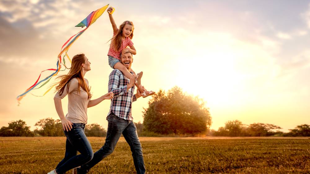 family running through field letting kite fly | Five Keys to Happiness | featured