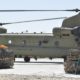 A US Army Boeing CH-47 Chinook sits on a airfield surrounded by supplies | US Military Equipment Left Behind in Afghanistan | featured