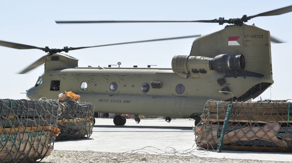 A US Army Boeing CH-47 Chinook sits on a airfield surrounded by supplies | US Military Equipment Left Behind in Afghanistan | featured