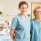 Portrait of confident nurses standing against couple with newborn baby at hospital