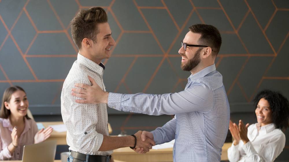 Team leader handshaking employee congratulating with professional achievement | Great Leaders Are Continuous Learners | featured