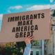 The phrase Immigrants Make America Great on a carton banner in men's hand | Case Against Immigration Activist Maru Mora Villalpando | featured