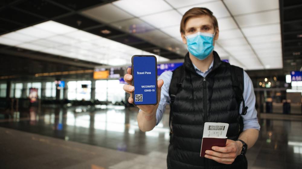 Travel Pass. Hand holding mobile Digital vaccine passport COVID-19 app | IATA Welcomes US Decision to Lift COVID-19 Travel Restrictions | featured