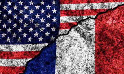 two flags of the USA and France on a cracked concrete wall | France Nixes US Gala, Alludes That Biden Is A Backstabber | featured