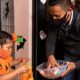 A man giving candies to a girl dressed in a pumpkin costume | Safe Trick Or Treating During COVID Halloween | featured