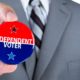 A man in a business suit holds out a political independent voter pin during elections | Independent Voters Are Dumping Joe Biden In Large Numbers | featured