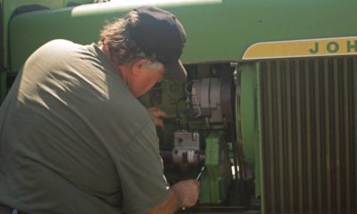 Cultural Equipment Mechanic working on an antique John Deere tractor | John Deere Workers Stage Walkout Then Went On Strike | featured
