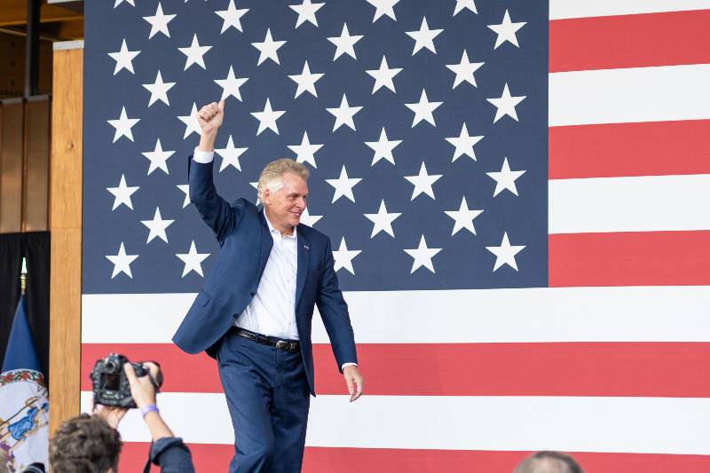 Terry McAuliffe waving to the crowd while walking on stage-McAuliffe