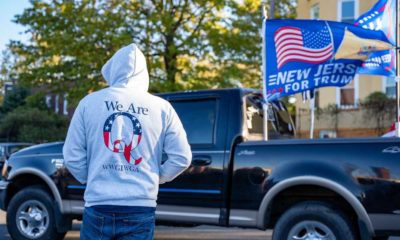 Hooded man wearing a Qanon sweatshirt at Trump Rally | QAnon Followers Gather in Dallas to Wait for JFK Jr to Reappear | featured