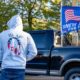 Hooded man wearing a Qanon sweatshirt at Trump Rally | QAnon Followers Gather in Dallas to Wait for JFK Jr to Reappear | featured