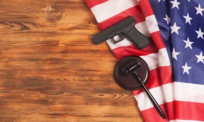 Judge gavel and gun on USA flag. Gun law concept | Support For Tighter Gun Control in 2021 Is Lowest In A Decade | featured