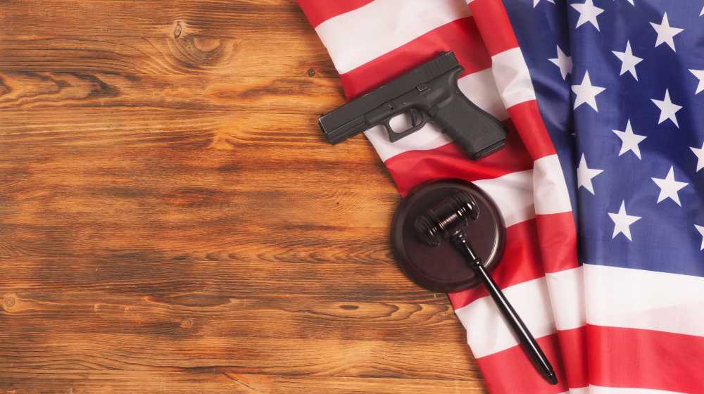 Judge gavel and gun on USA flag. Gun law concept | Support For Tighter Gun Control in 2021 Is Lowest In A Decade | featured