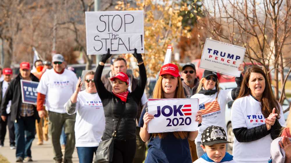 Pro Trump supporters at Stop the Steal rally holding signs against the media declaring Joe Biden President elect | NBC Poll: 22% Of GOP Voters Say Biden Didn’t Win 2020 Polls | featured
