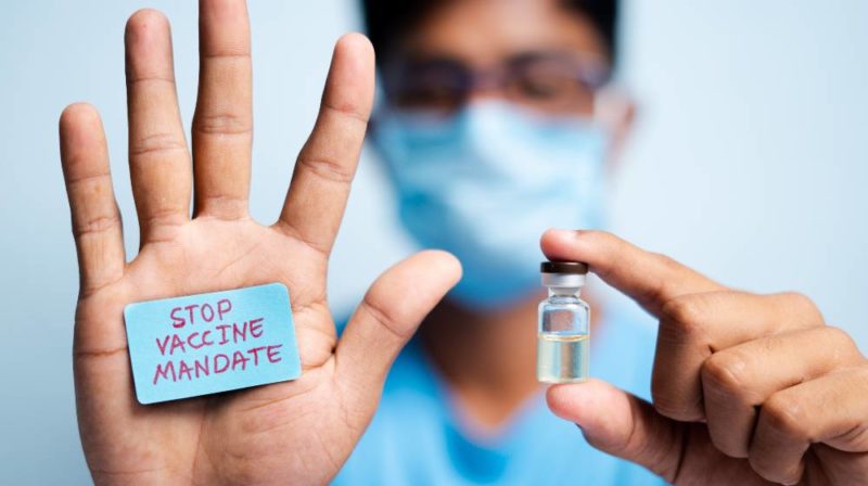 Young man with medical face mask showing stop vaccine mandate | CNN 5 Things