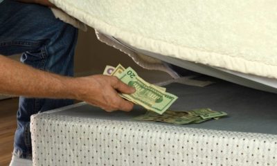 Man putting money under his mattress to save it showing no trust in financial institutions and banks | 8 Simple Ways To Save Money | featured