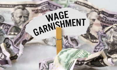 There are dollars on the table and there is a clothespin with paper on which it is written - WAGE GARNISHMENT | How to Make a Payment Arrangement to Stop Wage Garnishment | featured