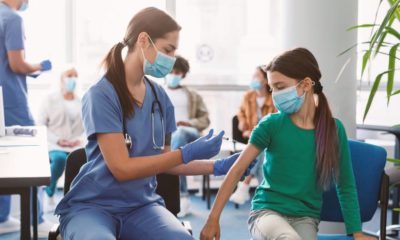 Doctor vaccinating child at clinic. Little girl getting flu shot | No Evidence That Healthy Kids and Adolescents Need COVID Booster Shots, Says WHO | featured