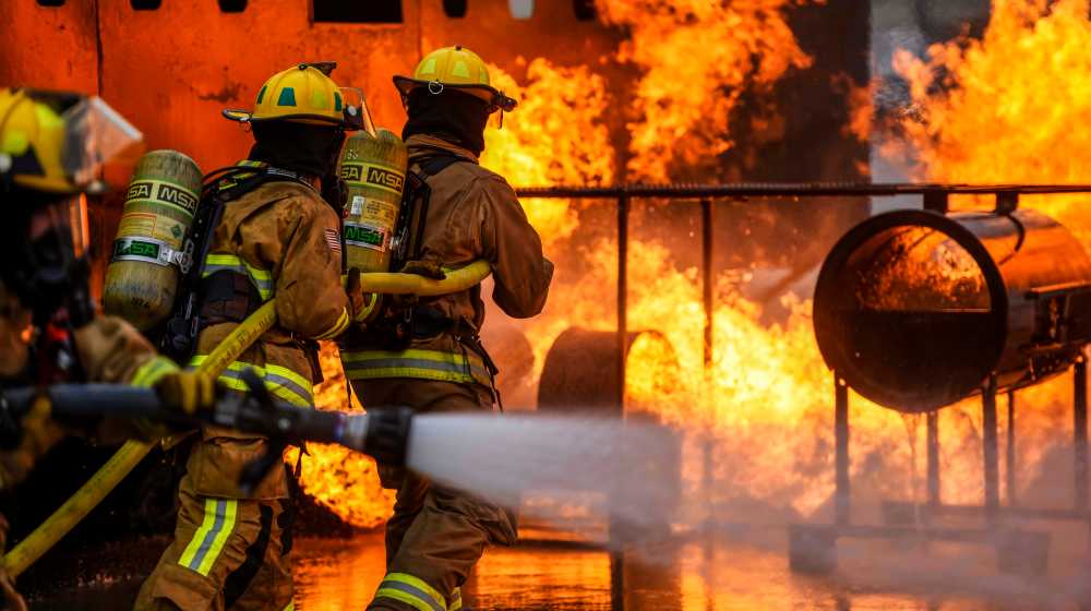 Fire brigade people extinguishing the fire, Fire brigade spreading water | New York’s Worst Fire Disaster in 30 Years Claims 19 Lives | featured
