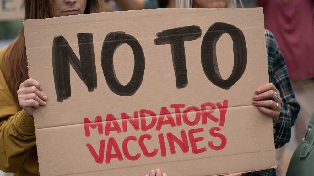 Group of no VAX deniers holding up a no to mandatory vaccines | Doubts On COVID Vaccine Fueling Bigger Anti-Vax Movement | featured