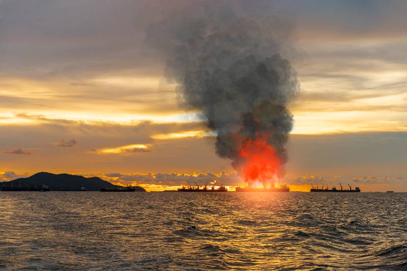 Large general cargo ship for logistic import export goods and other anchored at the offshore sea horizon the explosion and had a lot of fire | Cargo Ship Full of Luxury Cars Caught Fire During Atlantic Journey