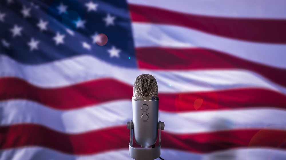 A Microphone In Front Of A USA Flag Ready For A Public Address From The President | Republicans Greet Biden’s State of the Union Address With Jeers | featured