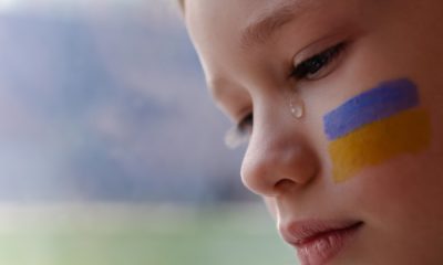 A child with the flag of Ukraine is crying | US To Accept 10,000 Ukrainian Refugees | featured