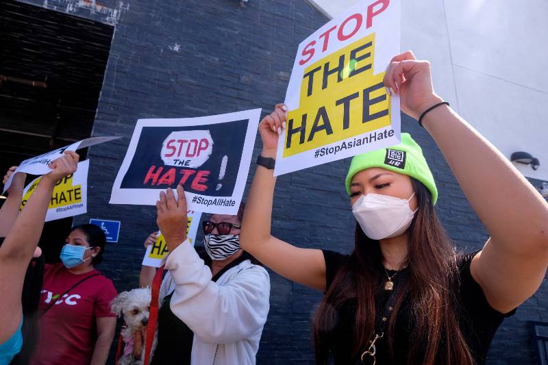 People hold signs to protest hate crimes committed against Asian-American | Why Anti-Asian Hate Rarely Becomes a Hate Crime
