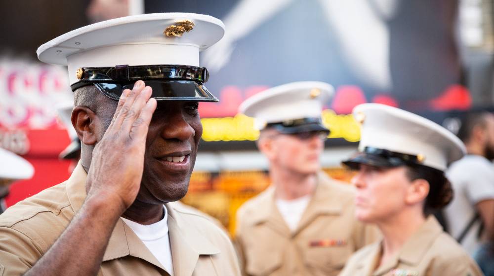 USMC officer salutes after a commemorative group photo on the red steps in Father Duffy Square during Fleet Week | Racism and Hate Should Not Be Part of the Military | featured