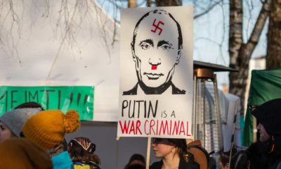 Woman hold banner with inscription Putin is a war criminal | Biden, Senate Call Putin A ‘War Criminal’ | featured