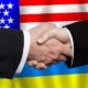 Business handshake on the background of American and Ukrainian flags | Don’t Use The South Border, Biden Tells Ukrainian Refugees | featured