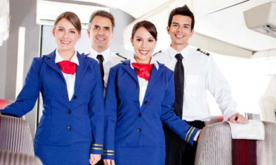Friendly cabin crew in an airplane smiling | Delta Flight Attendants Will Now Get Paid for Boarding Duties | featured