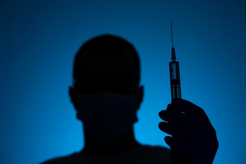 A doctor in a medical mask and gloves holds a syringe with a coronavirus vaccine | Fact-Checking Vaccination Conspiracy Theories!: 5 Examples
