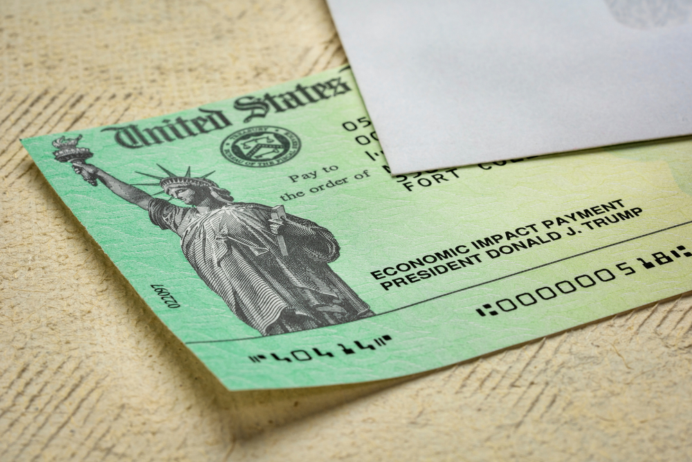 A stimulus check sample under a white letter envelope-Democrats Seek to Restart Stimulus Talks-ss-featured