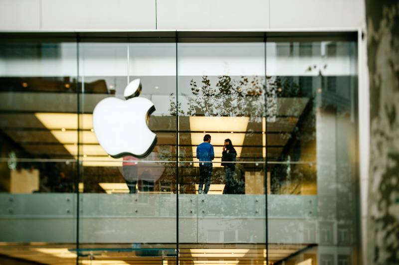 Apple Store logo and facade with Genius Employee explaining to a customer | Return to the Office