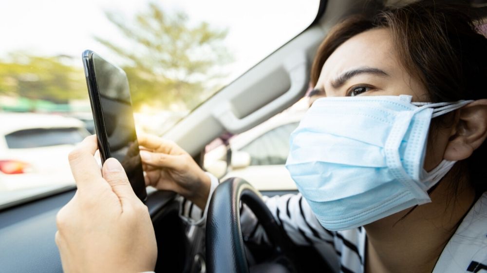 woman wearing a mask insider her car | Woman Licks Plane Toilet Seat for the “Coronavirus Challenge” and Gets Slammed by Twitter | Featured