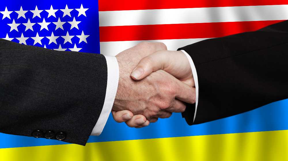 Business handshake on the background of American and Ukrainian flags | Don’t Use The South Border, Biden Tells Ukrainian Refugees | featured