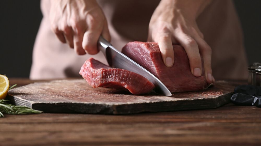man cutting a pork meat | Meat Alternatives Have Gone Mainstream, But How Can They Fit in Your Diet? | Featured