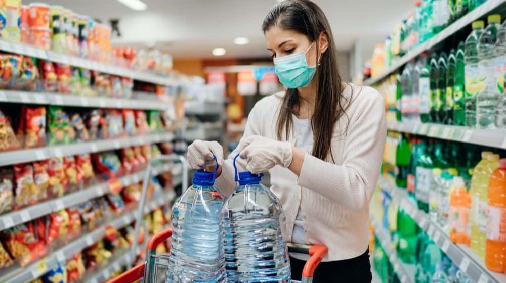 woman getting water in the supermarket | Fact Check: A Blanket National Quarantine is Likely Not Legal | Featured