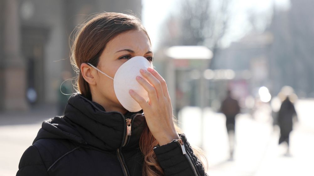 woman outside wearing a white face mask | The Head of the WHO Warns that 'The Worst' of the Coronavirus is 'Ahead of Us' | Featured